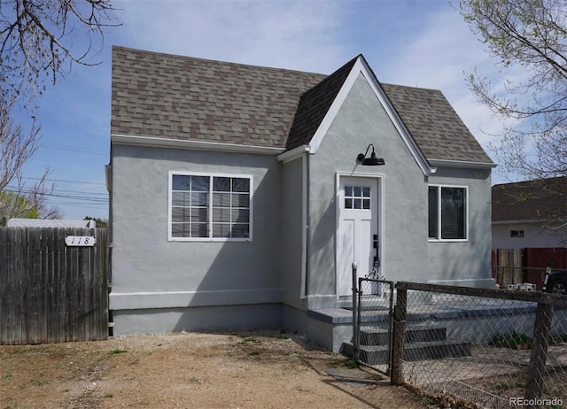 view of front of property with fence, a shingled roof, a gate, and stucco siding