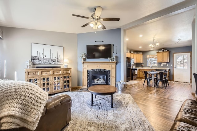 living area with a ceiling fan, a premium fireplace, and wood finished floors