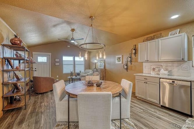 dining room featuring ceiling fan, vaulted ceiling, a textured ceiling, and light wood-type flooring