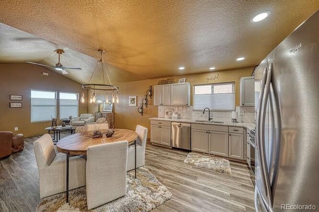 kitchen featuring sink, a textured ceiling, hanging light fixtures, stainless steel appliances, and backsplash