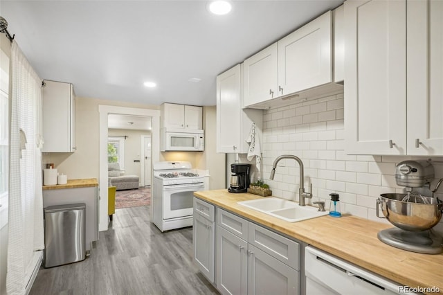 kitchen with white appliances, tasteful backsplash, wood finished floors, wooden counters, and a sink