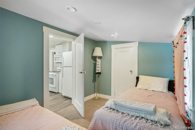 bedroom featuring a closet, light colored carpet, freestanding refrigerator, and baseboards