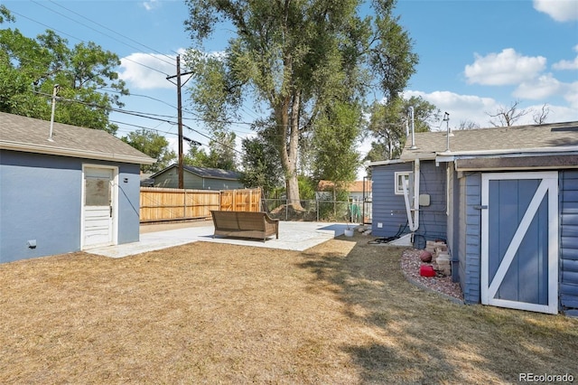 view of yard featuring a patio area, fence, and an outbuilding