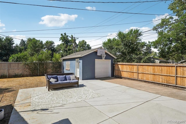 detached garage featuring concrete driveway and fence