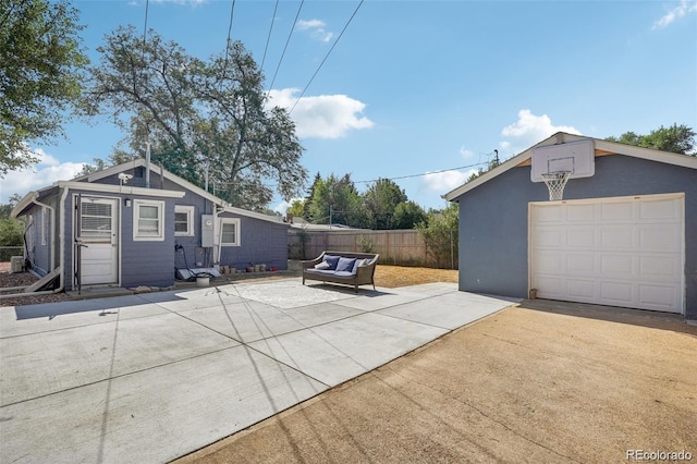 view of side of home with an outbuilding, concrete driveway, fence, and a garage