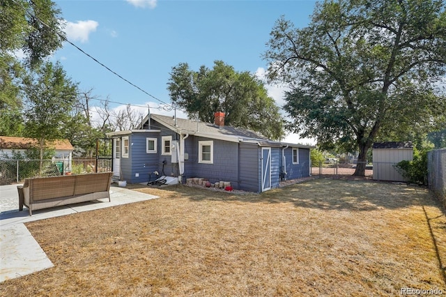 rear view of house with an outbuilding, a patio, a fenced backyard, a storage shed, and a yard