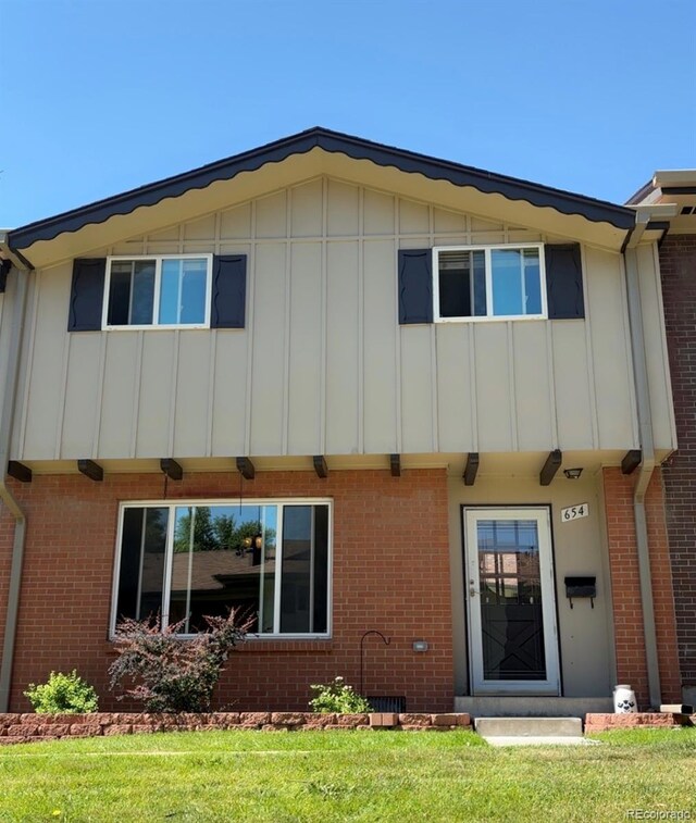 654 S Xenon Ct, Lakewood, CO 80228 - back of house featuring board and batten siding, brick siding, and a yard