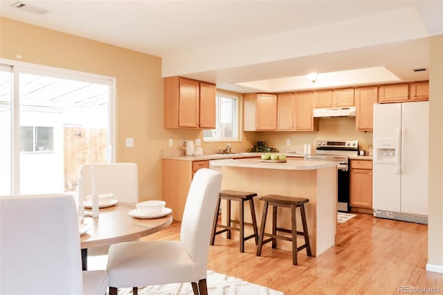 654 S Xenon Ct, Lakewood, CO 80228 - kitchen with white fridge with ice dispenser, stainless steel electric range, under cabinet range hood, light brown cabinets, and light countertops