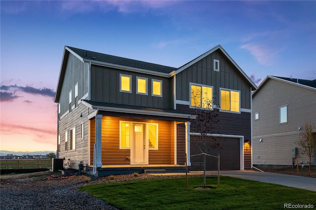 view of front of home with a garage, a yard, and central air condition unit