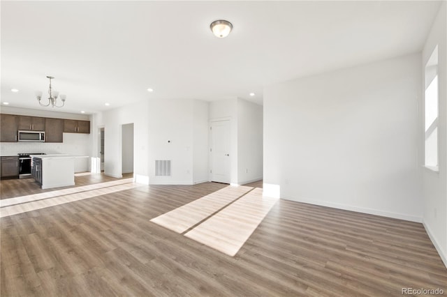 unfurnished living room featuring light wood-type flooring and a chandelier