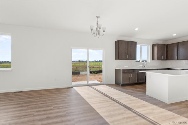 kitchen featuring sink, light hardwood / wood-style flooring, a chandelier, decorative light fixtures, and decorative backsplash