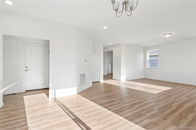 empty room with an inviting chandelier and light hardwood / wood-style flooring