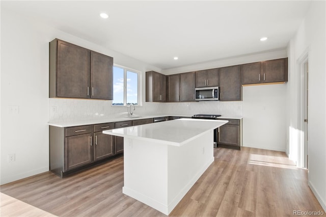 kitchen featuring a center island, backsplash, sink, light hardwood / wood-style floors, and dark brown cabinetry