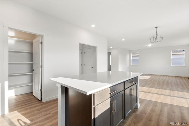 kitchen with dark brown cabinets, a kitchen island, light hardwood / wood-style floors, and decorative light fixtures