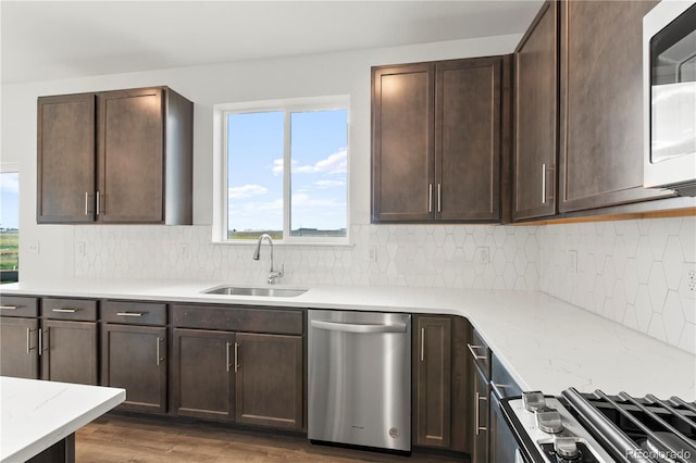 kitchen featuring stainless steel dishwasher, dark brown cabinets, dark hardwood / wood-style flooring, and sink