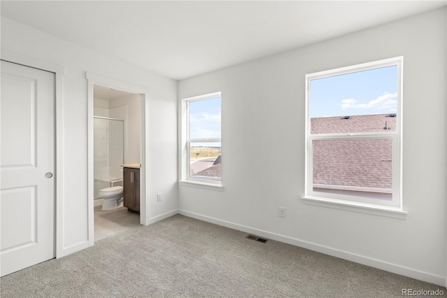 unfurnished bedroom featuring light carpet and connected bathroom