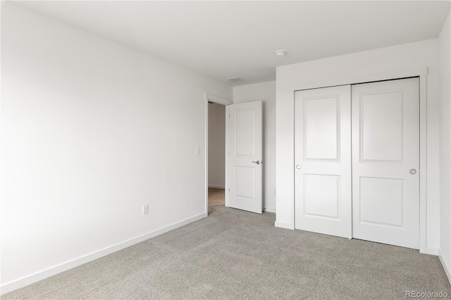 unfurnished bedroom with light colored carpet and a closet