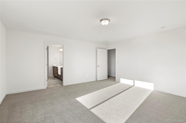 bedroom with ensuite bathroom and light carpet