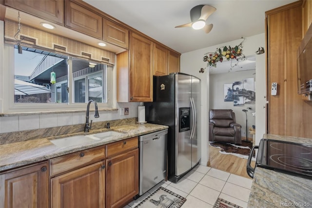 1164 W 101st Pl, Northglenn, CO 80260 - kitchen with stainless steel appliances, a sink, brown cabinets, light stone countertops, and light tile patterned flooring