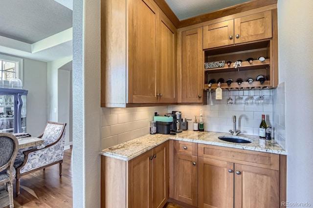 indoor wet bar featuring tasteful backsplash, wood finished floors, baseboards, and a textured ceiling