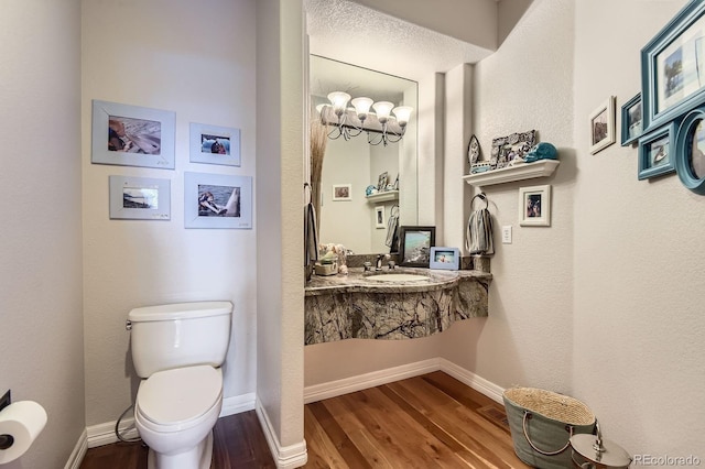 bathroom with wood finished floors, toilet, a sink, and baseboards