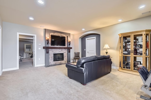 carpeted living area with a fireplace, baseboards, recessed lighting, and arched walkways