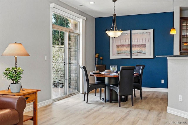 dining area featuring baseboards, visible vents, and wood finished floors