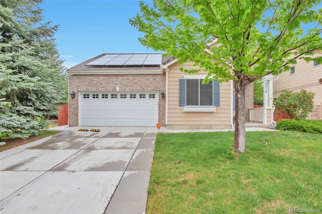 view of front of property featuring brick siding, an attached garage, concrete driveway, solar panels, and a front yard