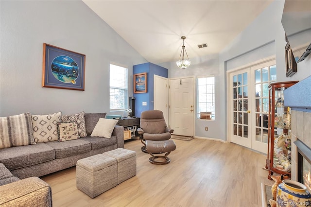 living room with light wood-type flooring, french doors, plenty of natural light, and vaulted ceiling