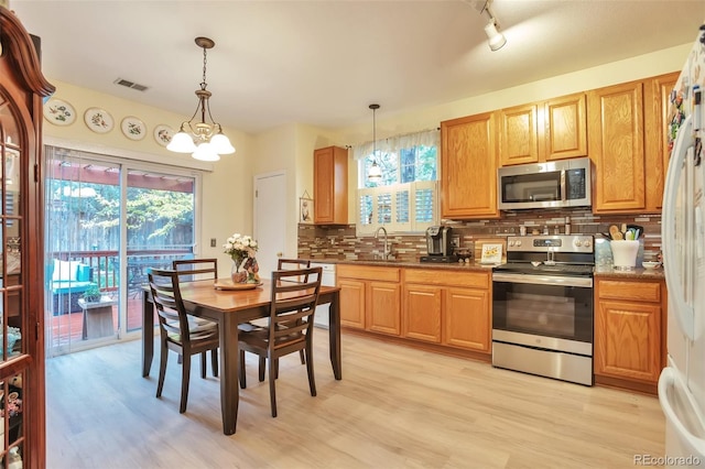 kitchen with stainless steel appliances, a sink, backsplash, and healthy amount of natural light