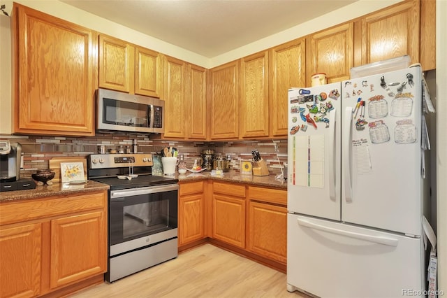 kitchen featuring stainless steel appliances, tasteful backsplash, and light wood-type flooring