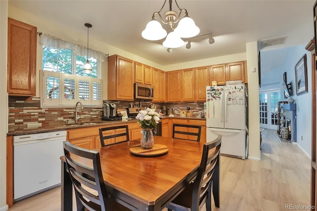 kitchen with appliances with stainless steel finishes, a chandelier, a sink, and decorative backsplash
