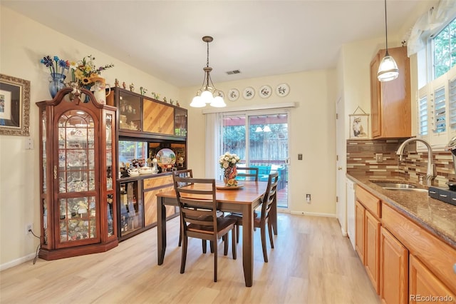 dining area featuring light wood-type flooring, a chandelier, and baseboards
