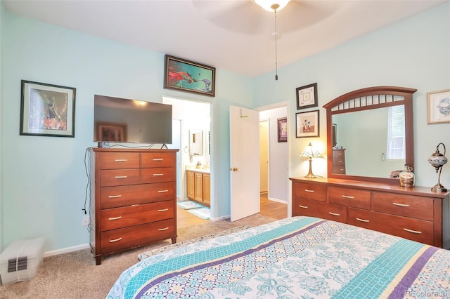 bedroom featuring light colored carpet, baseboards, and ensuite bathroom