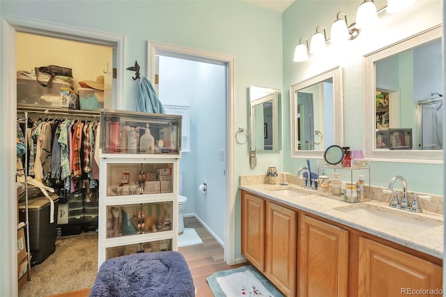 full bathroom with wood finished floors, toilet, double vanity, and a spacious closet