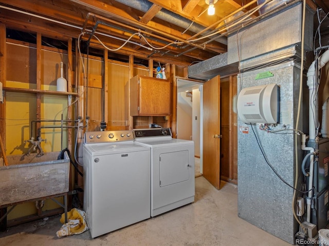 laundry area with heating unit, cabinets, sink, and washer and dryer