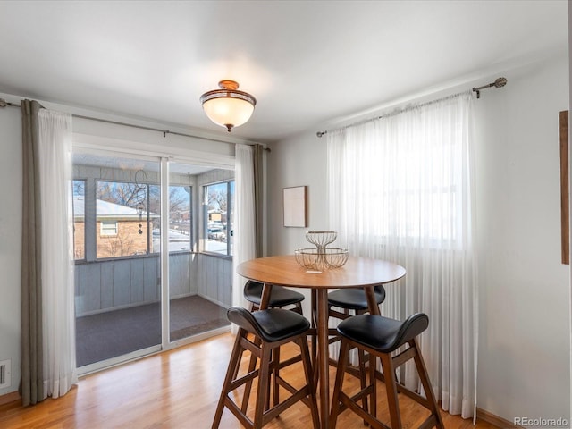 dining space with light hardwood / wood-style flooring and a healthy amount of sunlight