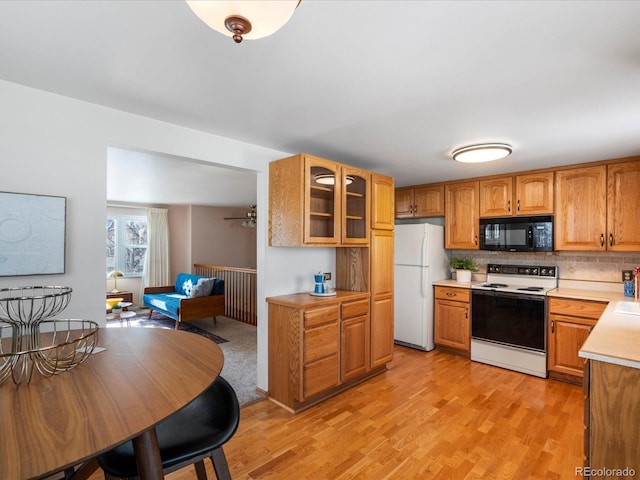 kitchen with tasteful backsplash, light wood-type flooring, and white appliances