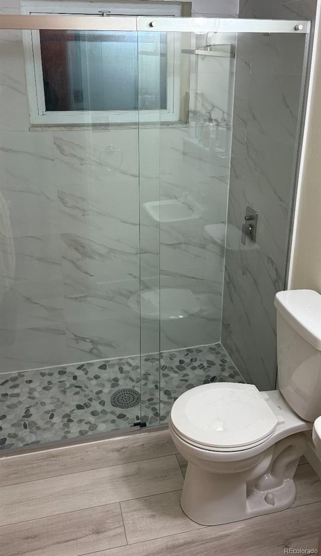 bathroom with a shower with shower door and toilet