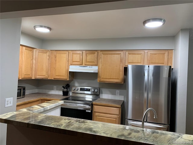 kitchen featuring stainless steel appliances, dark stone countertops, light brown cabinetry, and sink