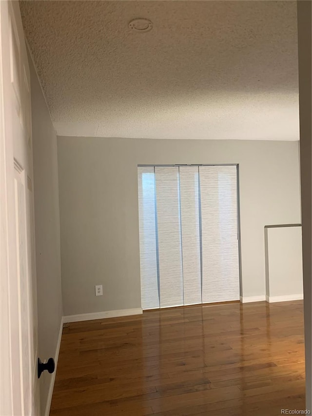 empty room with a textured ceiling and dark wood-type flooring