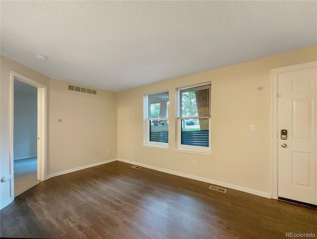 unfurnished room with a textured ceiling and dark hardwood / wood-style floors