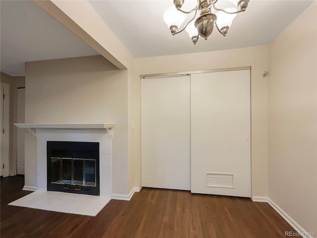 unfurnished living room featuring a fireplace, hardwood / wood-style floors, and an inviting chandelier