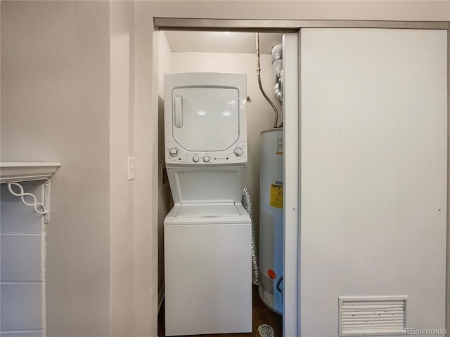 clothes washing area featuring gas water heater and stacked washing maching and dryer