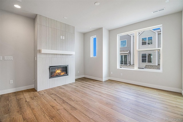 unfurnished living room with light hardwood / wood-style floors and a large fireplace