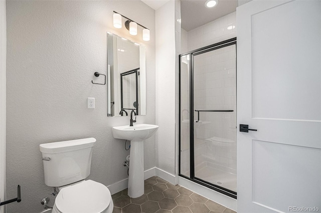 bathroom with sink, a shower with door, toilet, and tile patterned floors