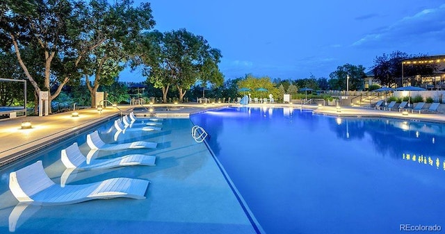 pool at dusk with a patio area