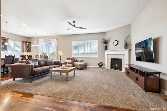 living room with ceiling fan with notable chandelier and hardwood / wood-style flooring