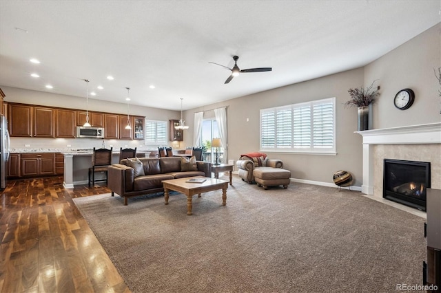 living room with ceiling fan, dark hardwood / wood-style floors, a fireplace, and a wealth of natural light