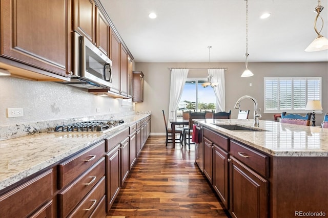 kitchen featuring sink, dark hardwood / wood-style floors, an island with sink, decorative light fixtures, and appliances with stainless steel finishes